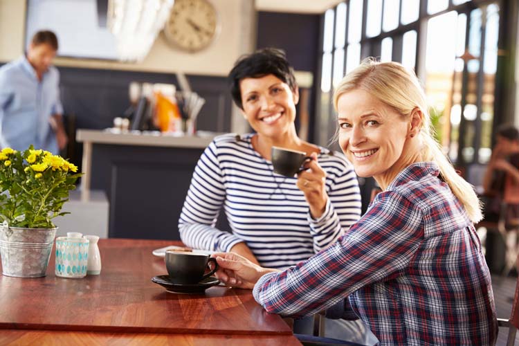 two happy women enjoying coffee at a cafe - sponsorship in aa - victory addiction recovery center - lafayette louisiana alcohol addiction treatment center