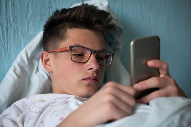 teenage boy on phone in bed