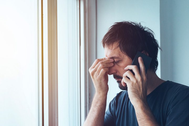 man on phone pinching bridge of his nose