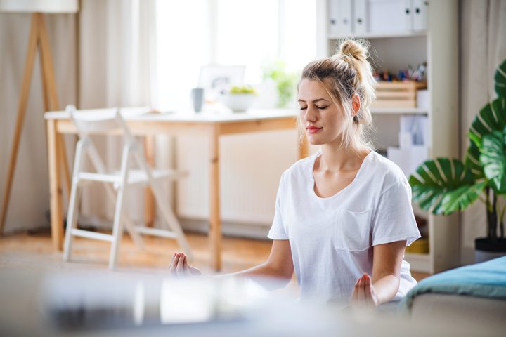 woman meditating at home on floor - prevent relapse