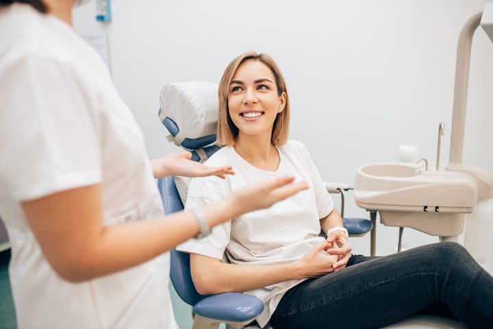 young woman in exam chair talking to dentist