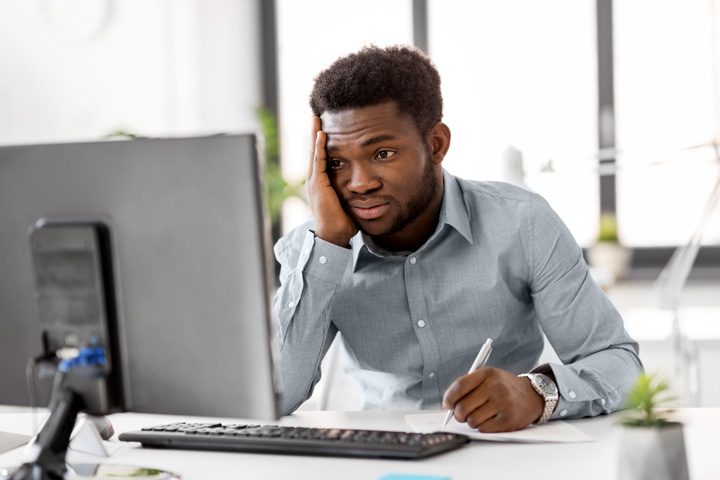 stressed handsome Black man at corporate job sitting in front of computer