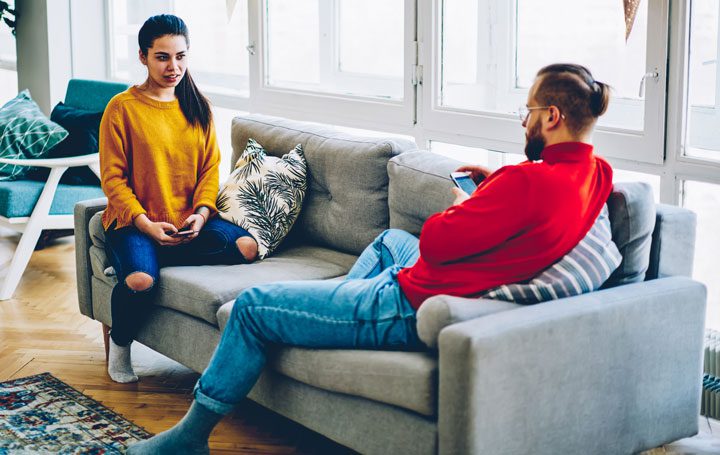 young couple sitting on couch having serious discussion - your spouse