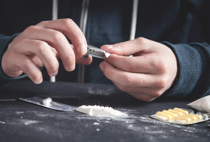 closeup of young man using white powdered drug on a table with several drugs - stimulants