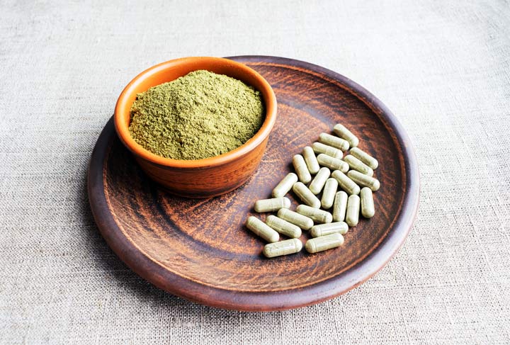 wooden plate and bowl with kratom powder and capsules - kratom addiction