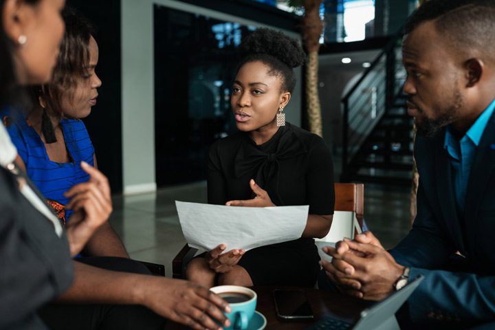 group of professional Black men and women talking and going over papers in a lobby seating area - drug addiction treatment