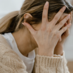 A woman covering her face with her hands.