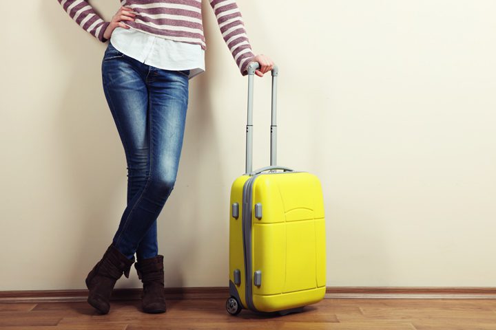 cropped shot - woman with bright yellow suitcase - hand on hip - inpatient