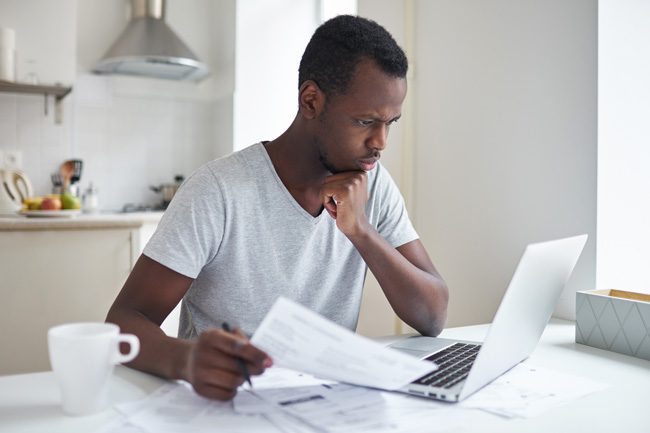 man looking at papers and laptop