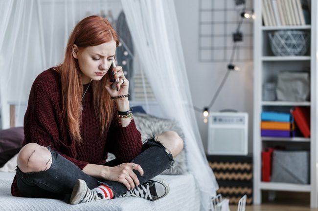 Drug Slang and Warning Signs: What Parents of Teens Need to Know - young red haired girl sitting on bed talking on cell phone