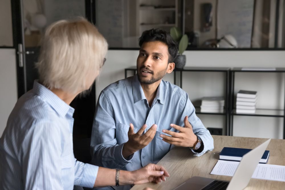 Man and woman sitting at a desk having a serious discussion in an office setting
