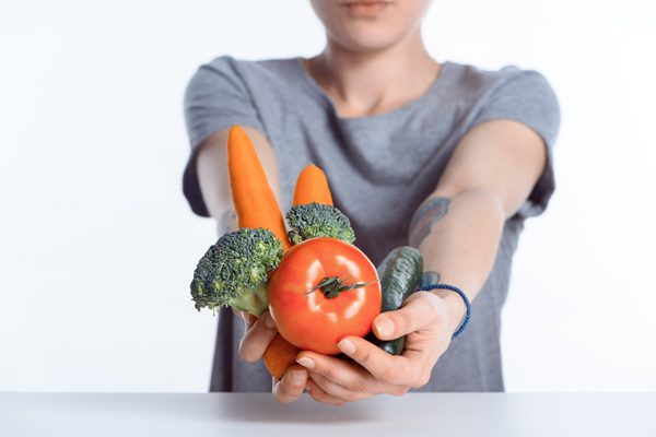 Foods Your Body Needs in Recovery - woman holding out fresh vegetables