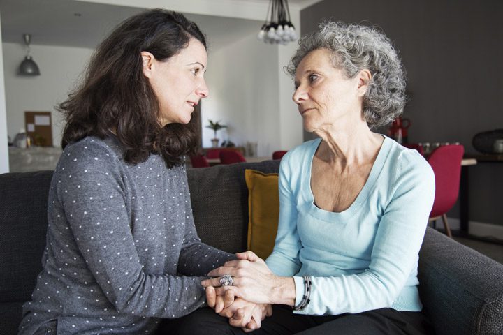 middle age woman having serious conversation with her senior mother - parent