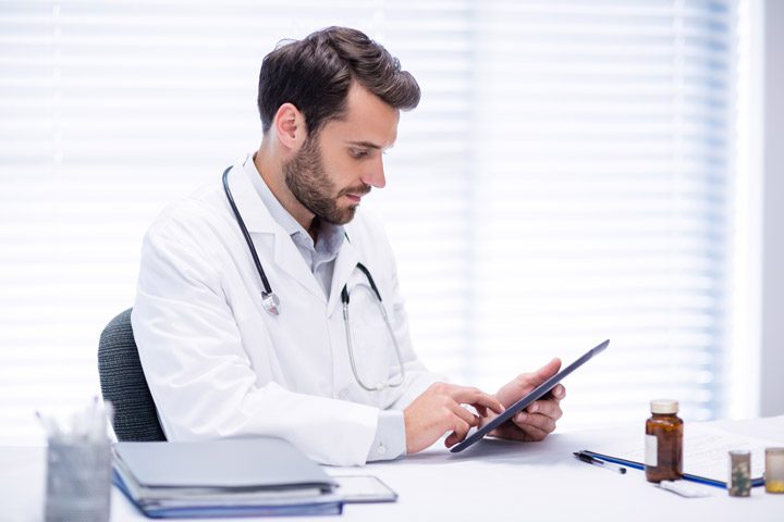 handsome young male doctor using tablet computer at his desk - benzo addiction